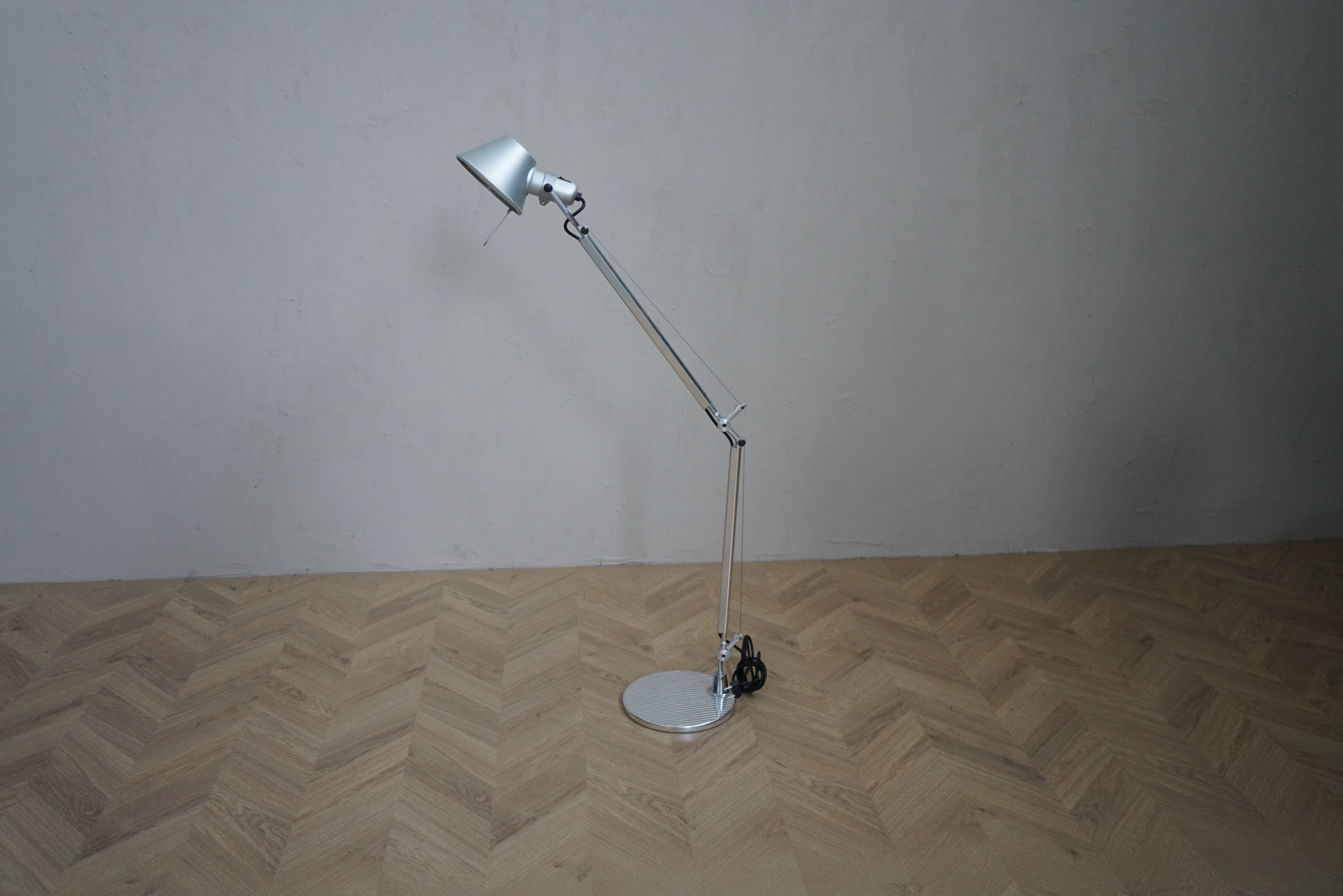 Artemide Tolomeo bordlampe i aluminium med rund fod, justerbar arm og bevægeligt lampehoved, set forfra.