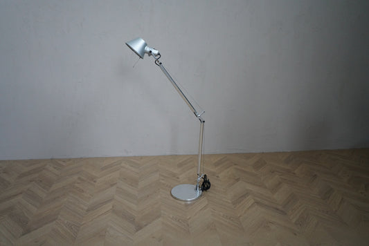 Artemide Tolomeo bordlampe i aluminium med rund fod, justerbar arm og bevægeligt lampehoved, set forfra.