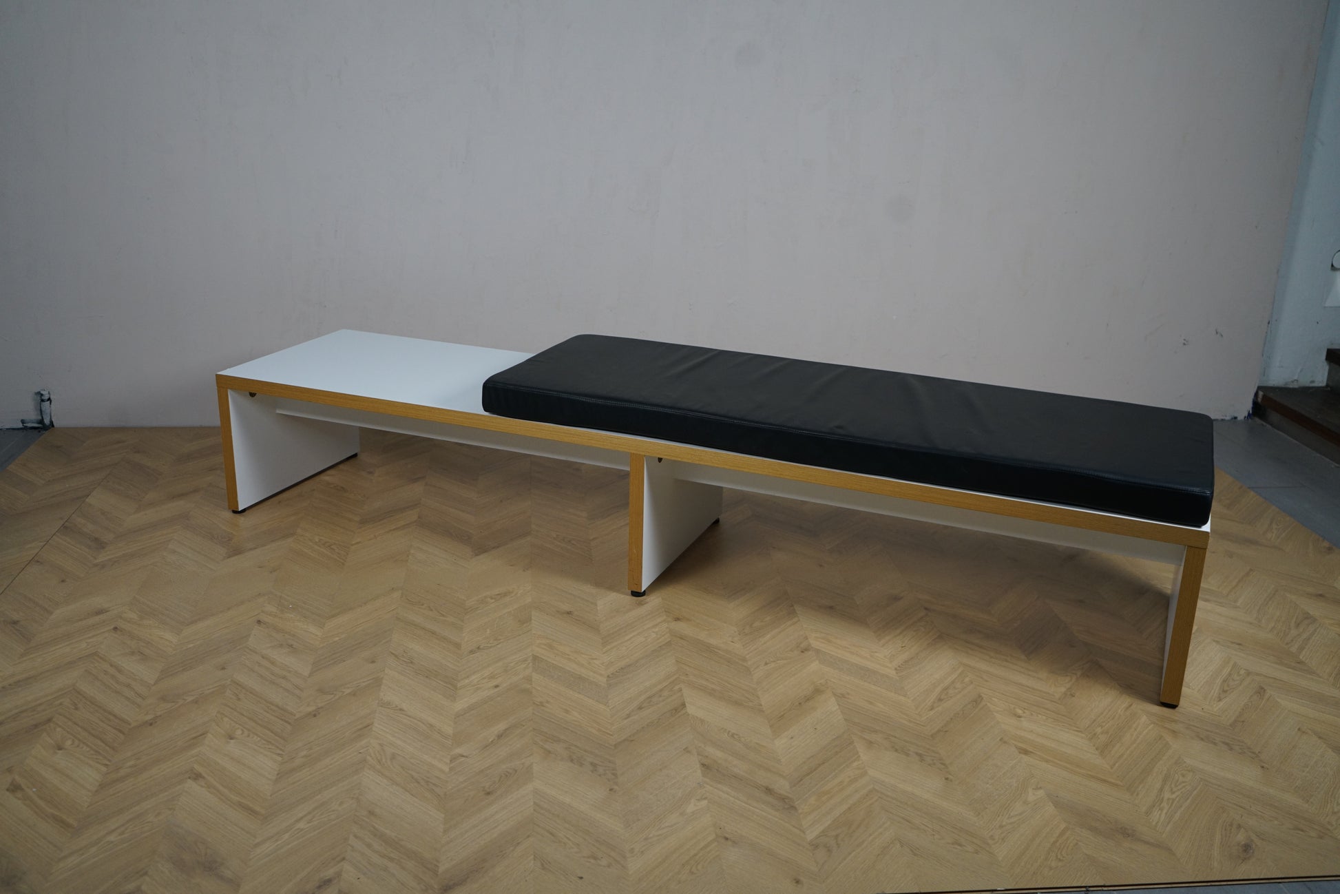 Moderne bænk 255x60x43 cm med sort hynde set skråt fra venstre – funktionel løsning til arbejdsplads og skole