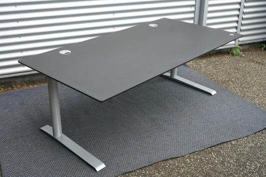 Cube Design hæve-sænkebord 180x90 cm med sort linoleum bordplade og gråt stel, set fra skrå vinkel.
