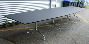 Dencon Delta konferencebord i sort linoleum set i skrå vinkel, viser tøndeformet bordplade og affasede kanter.