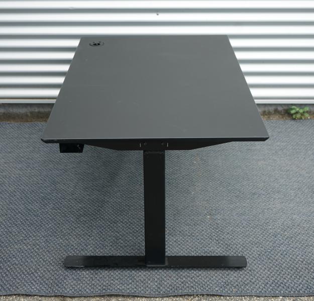 Sideprofil af Dencon hæve-sænkebord 130x80 med sort linoleum bordplade og sort understel.