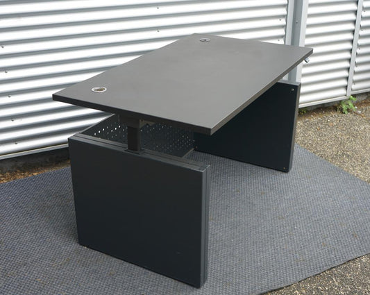 Dencon hæve-sænkebord 140x80 cm All Black Edition med sort linoleum bordplade og Linak motor, set fra skrå vinkel.