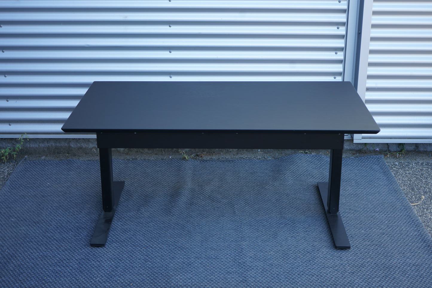 Dencon hæve-sænkebord 140x80 i sort linoleum med sort stel set direkte bagfra