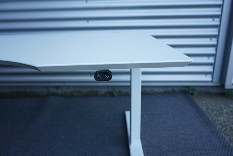 Close-up af Dencon hæve-sænkebord 160x90 med detalje af hvid laminat bordplade og elegant mavebue.
