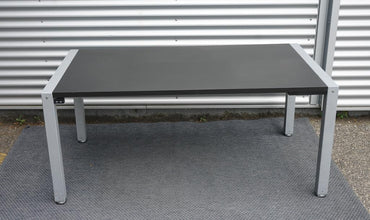 Frontbillede af Dencon hæve-sænkebord 160x90 med sort linoleum og firbenet gråt stel.