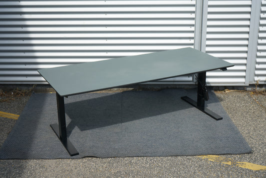 Dencon hæve-sænkebord 180x80 cm med mørkegrå bordplade og sorte ben – set fra skrå vinkel, ergonomisk skrivebord