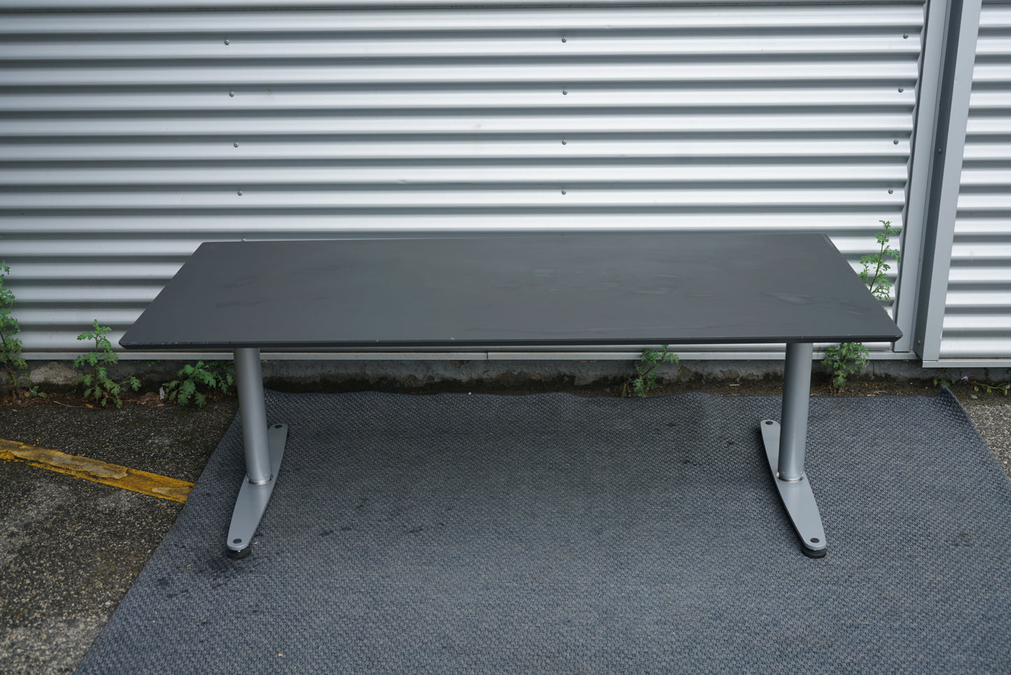 Dencon hæve-sænkebord 180x80 cm sort set bagfra med kabelbakke og justerbare ben.