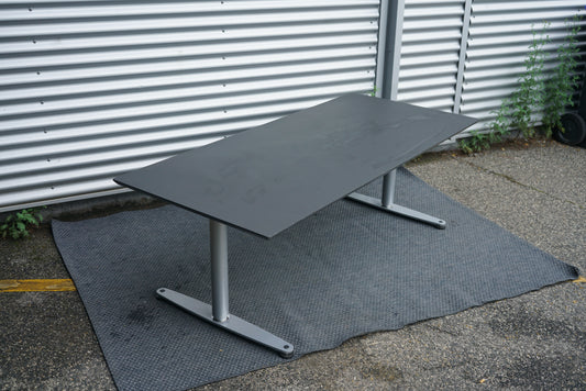 Dencon hæve-sænkebord 180x80 cm sort med linoleum bordplade, vist fra skrå vinkel med affasede kanter og kabelbakke.