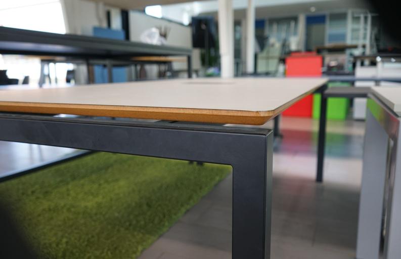 Nærbillede af kabelgennemføring og stikkontakter på Dencon konferencebord med beige bordplade og sort stel