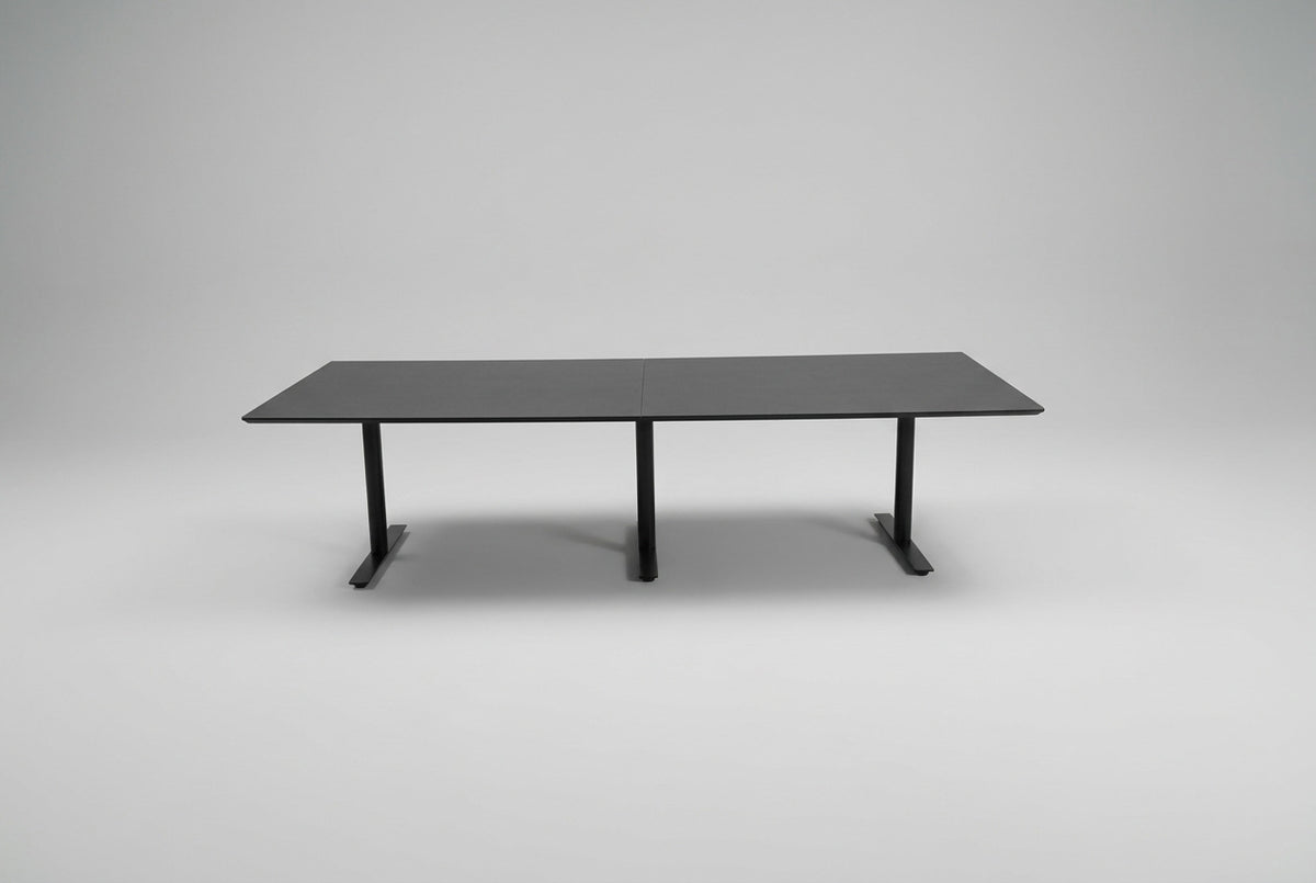 Dencon mødebord i sort linoleum på 280 x 110 cm med tre sorte T-formede ben set forfra.