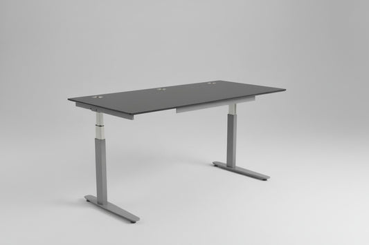 Brugt Duba hæve-sænkebord 180x80 i antracitgrå set fra skrå vinkel, med affasede kanter, kabelbakke og kabelgennemføring.