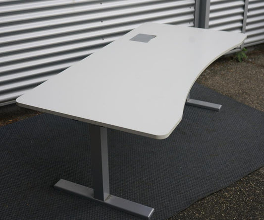 Duba hæve-sænkebord 180x90 cm i hvid med mavebue og kabelgennemføring, set fra skrå vinkel med gråt stel.