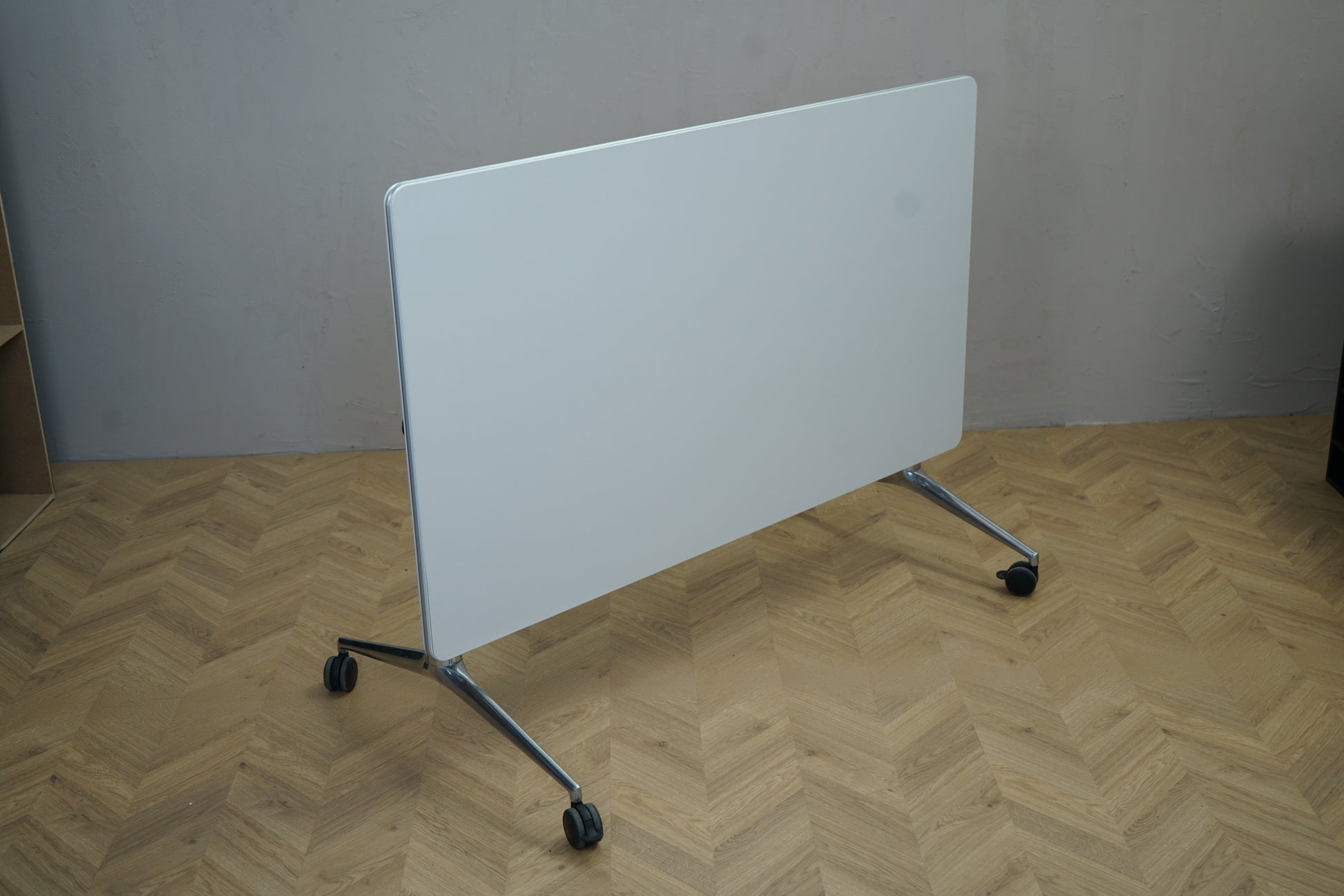 Sammenklappet Four Design klapbord på hjul 140x80 cm i hvid – set fra skrå vinkel, pladsbesparende løsning til kontor og konferencer.