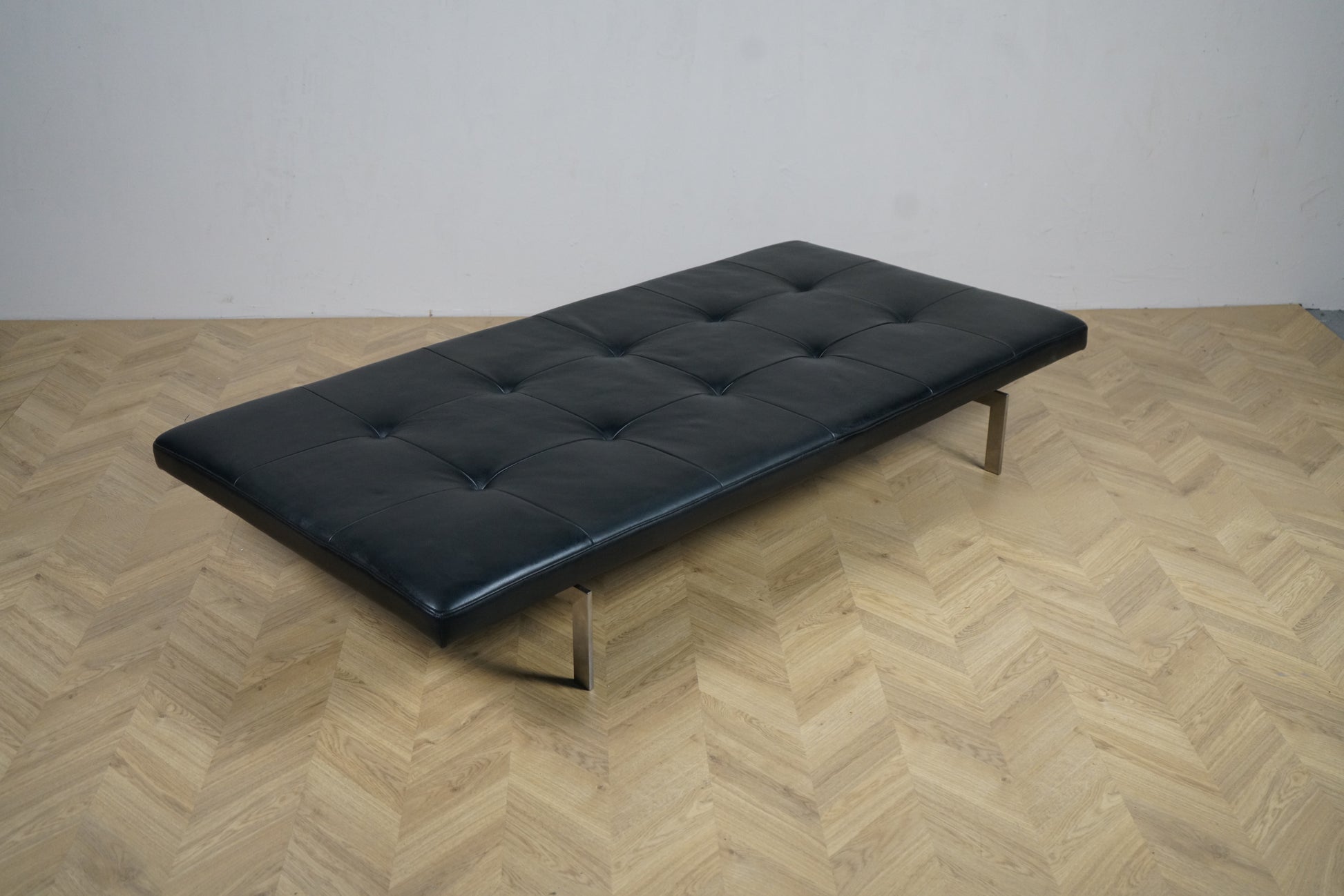 Fritz Hansen PK80 dagseng i sort læder set skrå fra højre med forkromede stålben, design Poul Kjærholm.