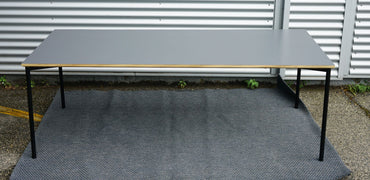 Fumac bord 210x90 i antracitgrå med flot bordplade og krydsfinerkanter set forfra.