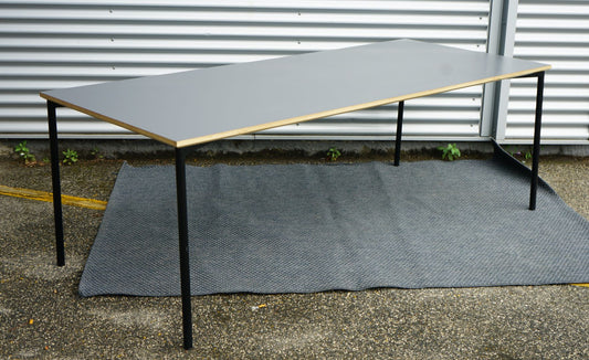 Fumac bord 210x90 i antracitgrå med elegante krydsfinerkanter set fra skrå vinkel.