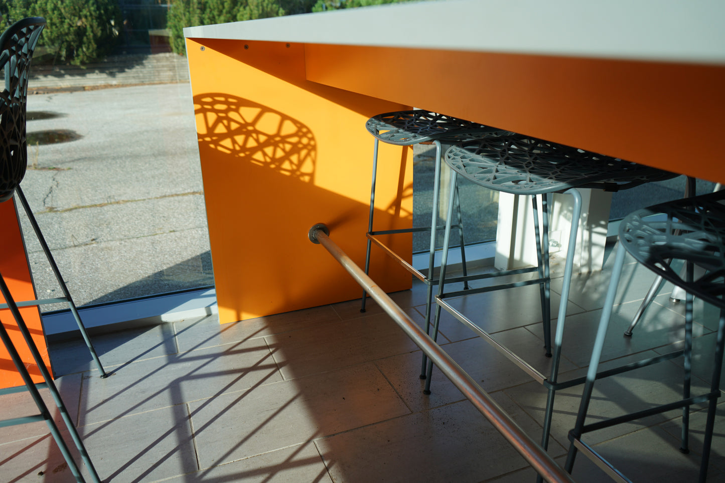 Detalje af lysegrå Fumac højbord med orange sidepanel og stålstøtter.