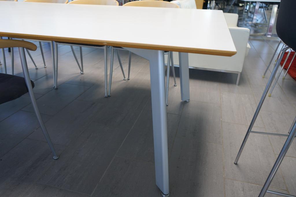 Nærbillede af Fumac bordets kant og laminatfinish – hvid bordplade i ét stykke med gråt stel i høj kvalitet.