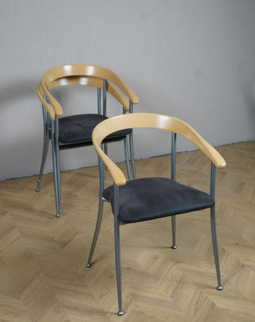 Fumac Milano stol i skråt perspektiv – mørkegrå sædepolstring, gråt stel og lakeret ahorn ryglæn.