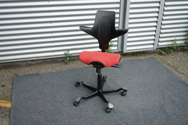 Skrå billede af Håg Capisco 8020 sadelstol i rød stof med sort stel