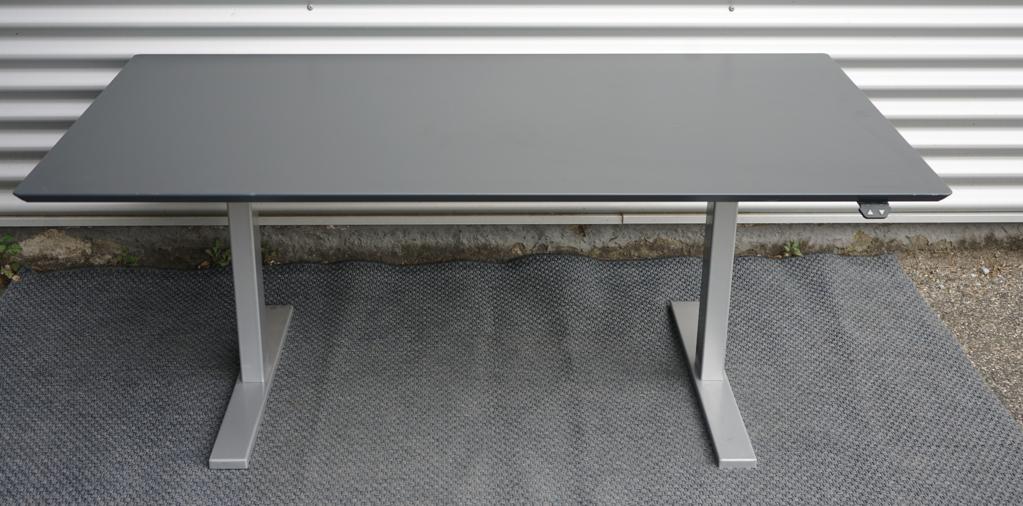 Bagfra billede af Holmris hæve-sænkebord 160x90 i antracitgrå med kabelbakke og gråt stel.