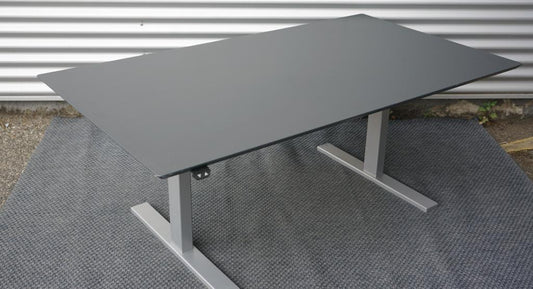 Skråt billede af Holmris hæve-sænkebord 160x90 i antracitgrå med kabelbakke og affasede kanter.