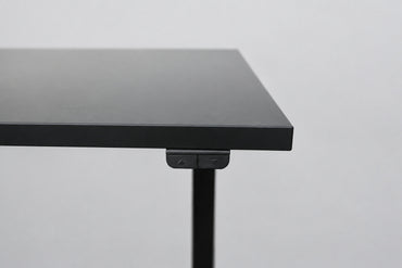 Close up af IKEA hæve-sænkebord med sort laminatbordplade og sort stel