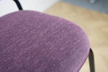 Nærbillede af lilla polstret sæde på Kinnarps barstol med sort stel