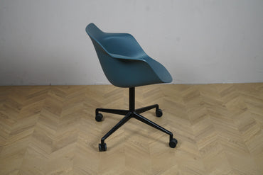 Moderne blå skaldstol fra Kinnarps med hjul og sorte ben set fra siden