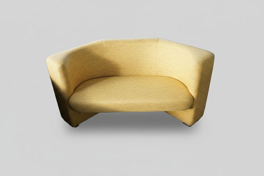 Kinnarps gul sofa med afrundet design og struktureret møbelstof, set forfra.