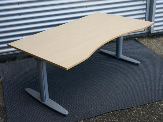 Hæve-sænkebord fra Kinnarps 160x90 cm i ahornfiner med gråt stel, set fra skrå vinkel med elegant mavebue og kabelbakke.