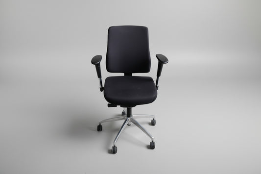 Sort kontorstol i Extreme-stof set forfra med regulerbare armlæn og fodkryds med gummibanehjul.