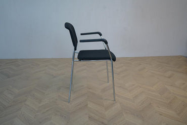 Sideprofil af Magnus Olesen Pause konferencestol med sort polstring og armlæn