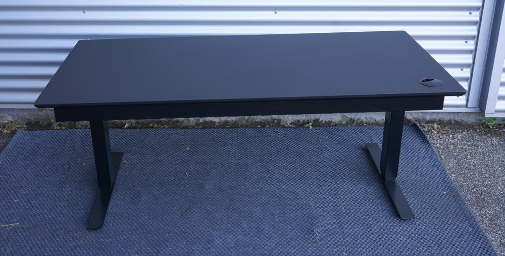 Bagfra visning af Martela hæve-sænkebord 160x80 cm i sort linoleum med kabelbakke og robust stel.