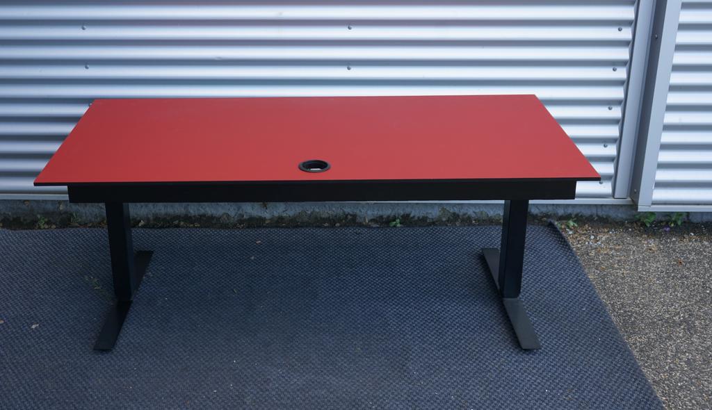 Martela hæve-sænkebord i rød linoleum 160x80 cm set bagfra – kabelbakke og stel i robust design til professionel brug.