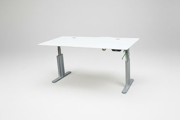 Montana hæve-sænkebord fotograferet fra skrå vinkel med hvid bordplade og sølv stel, 180x90 cm med kabelgennemføringer.
