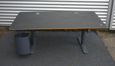 Frontvisning af Montana HiLow hæve-sænkebord i sort linoleum med integreret betjening og sort stel.