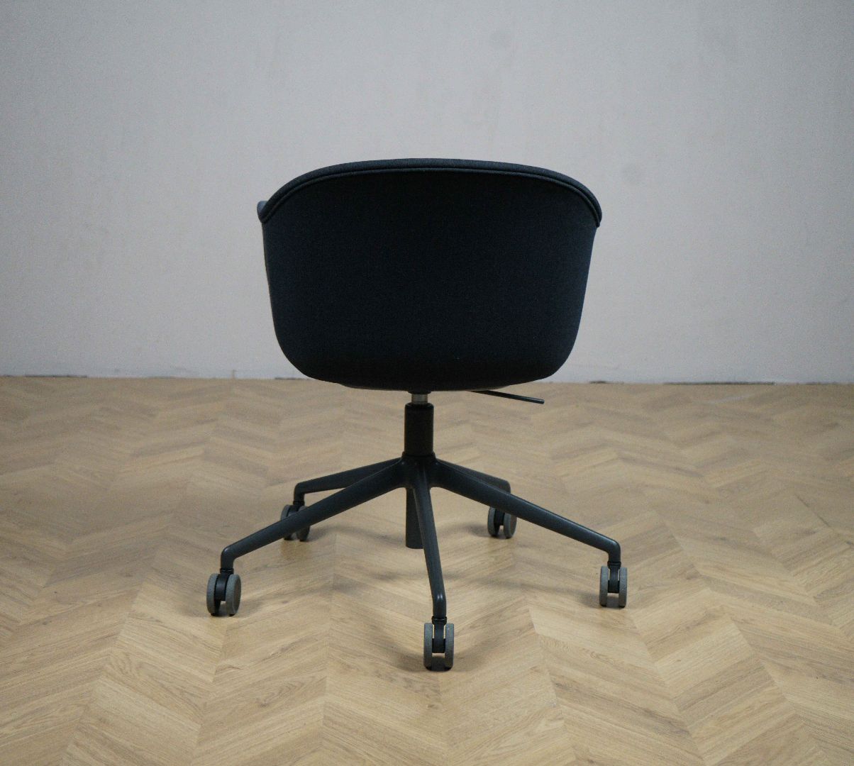 Muuto Fiber kontorstol i mørkeblå set bagfra – moderne design med sort hjulstel og ergonomisk form.