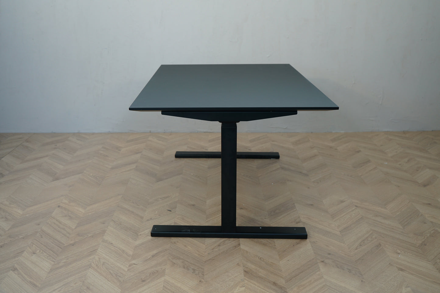 Paustian hæve-sænkebord med sort linoleum og sort stel set fra siden.