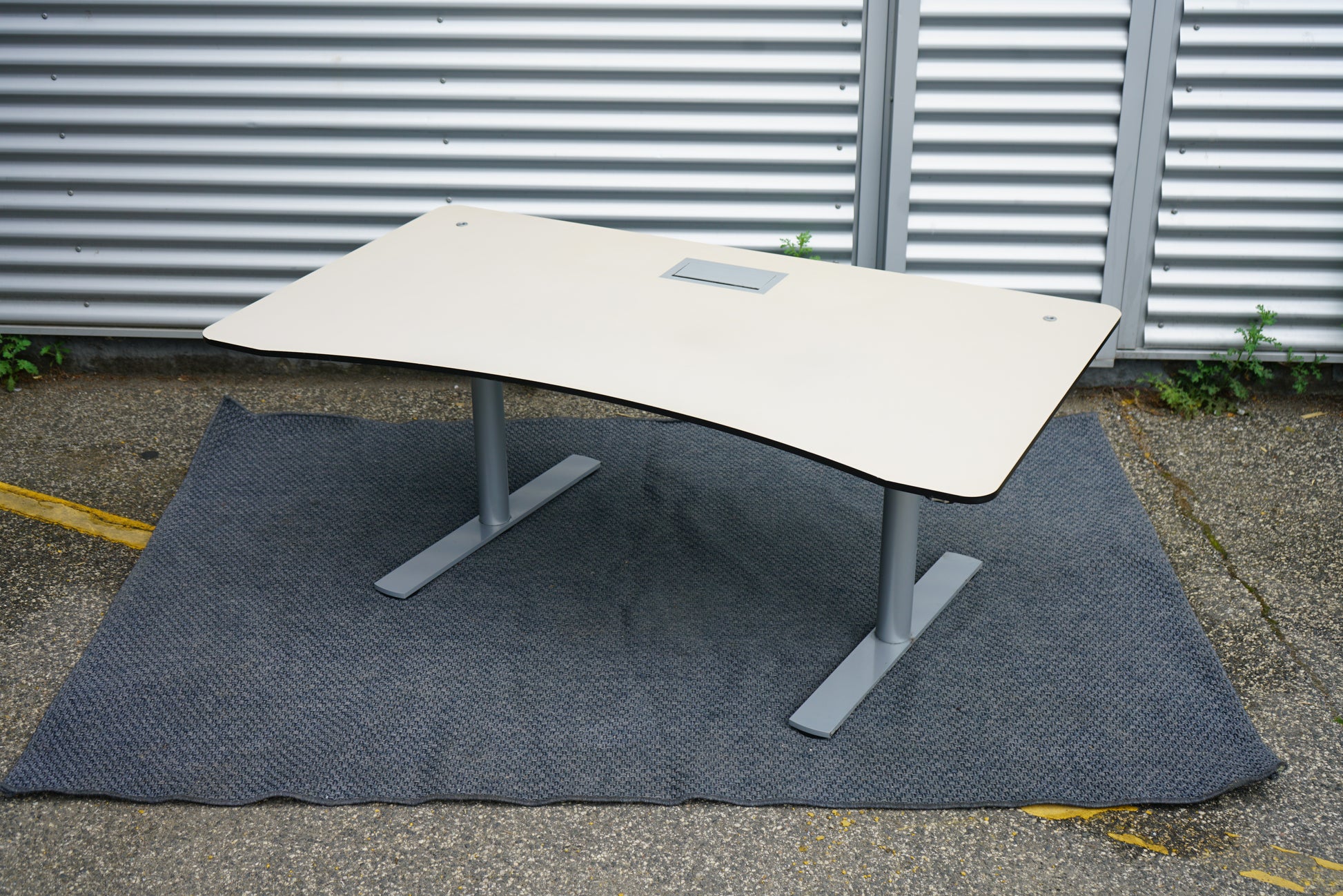 Sidevisning af Paustian hæve-sænkebord i beige med elegant mavebue og kabelgennemføring.