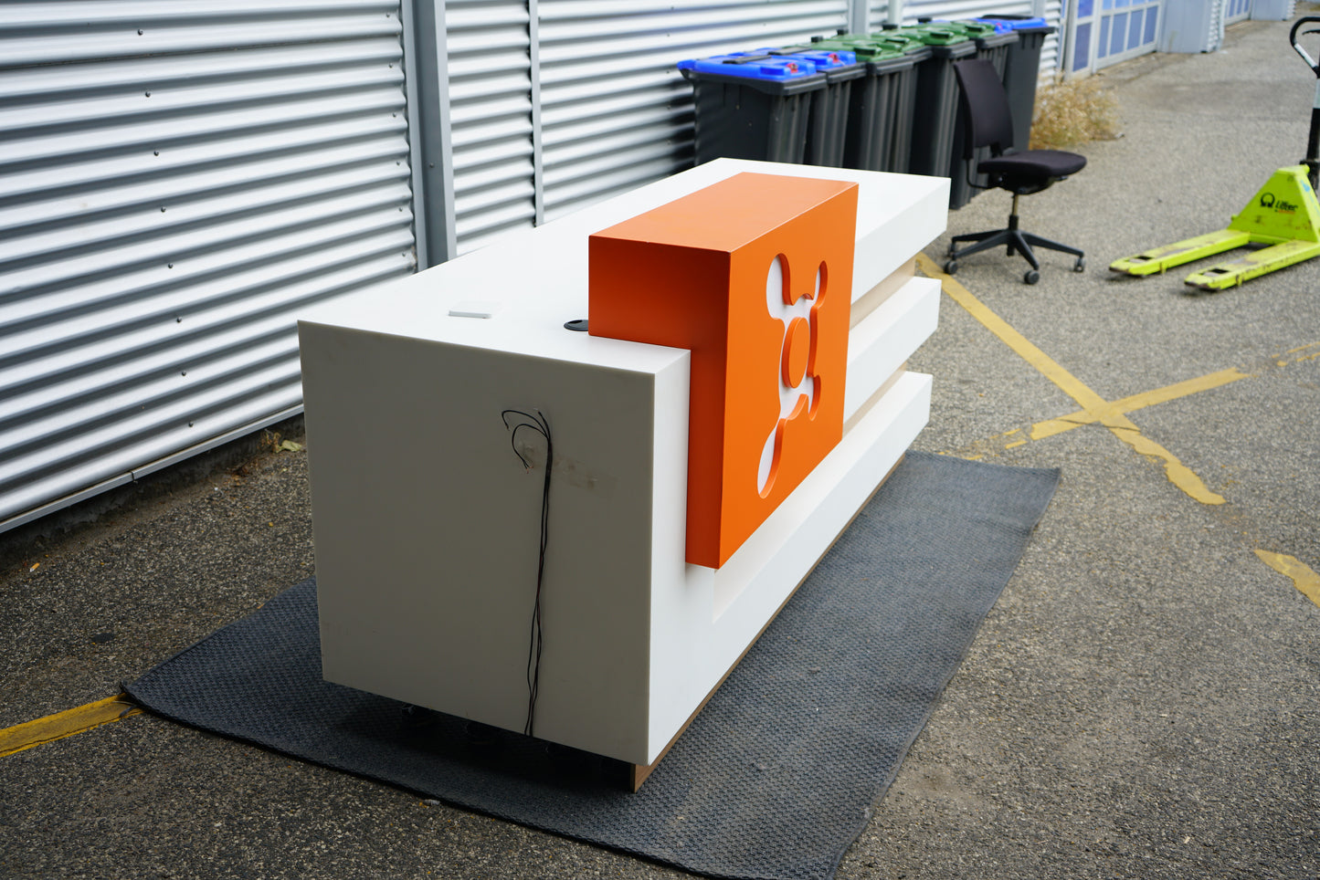 Skrå sidevinkel af receptionsbordet i hvid, træ og orange front.