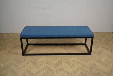 Rumas loungebænk med blå polstring og sort metalstel set fra skrå vinkel.