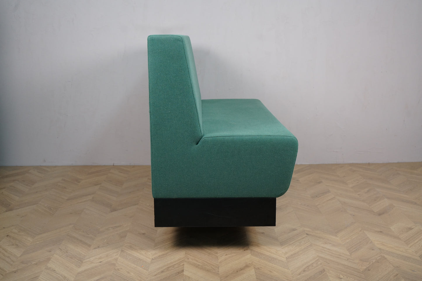Detaljebillede af Rumas lounge-sofa med lysegrøn polstring og sort base.