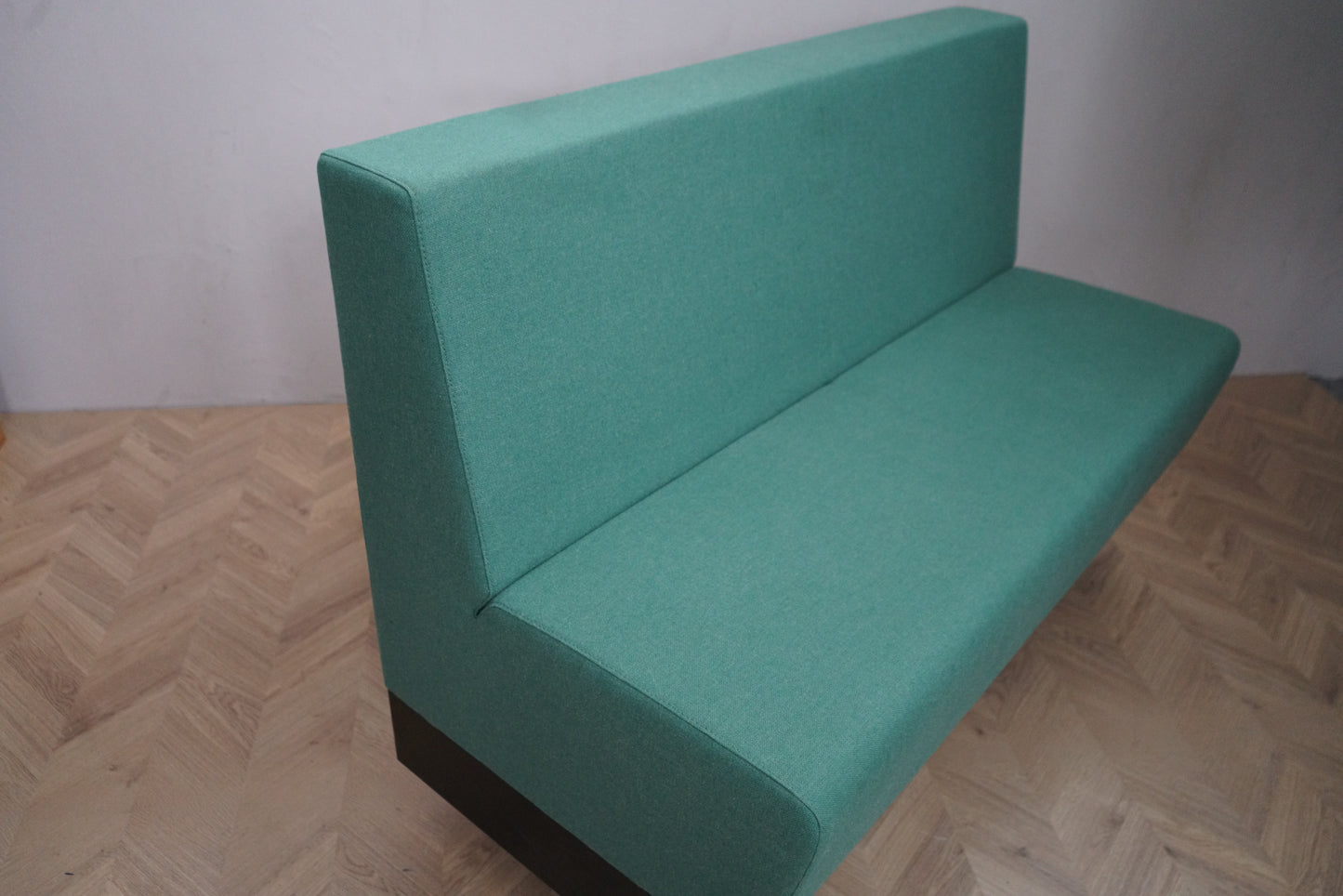 Detaljebillede af Rumas lounge-sofa med lysegrøn polstring og sort base.