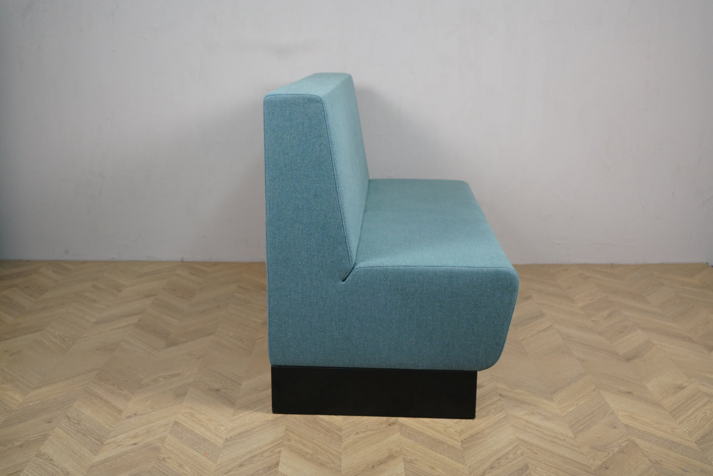 Rumas lounge med lys polstret sæde og ryg i moderne design set fra skrå vinkel.