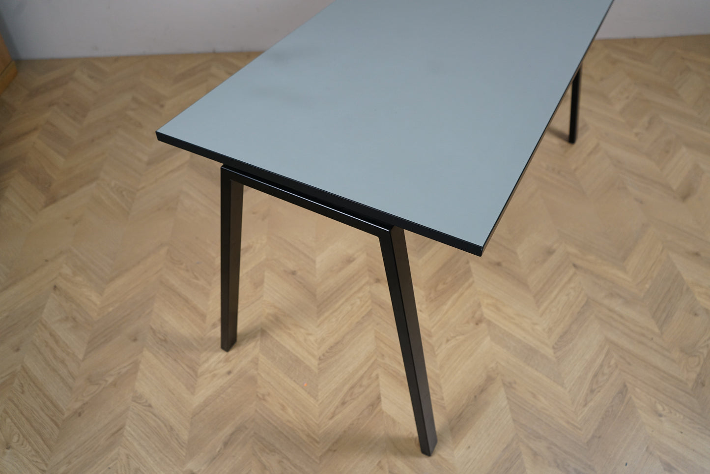 Detaljebillede af Rumas skrivebord med grå bordplade og elegante sorte ben.