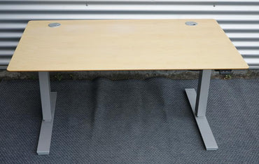 Frontbillede af Scanoffice hæve-sænkebord 140x80 i ahornfiner med gråt understel, kabelbakke og kabelgennemføring.