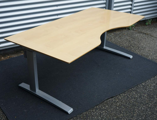 Skråt billede af Scanoffice hæve-sænkebord 180x90 med bordplade i bøg og lysegråt stel med elegant mavebue.
