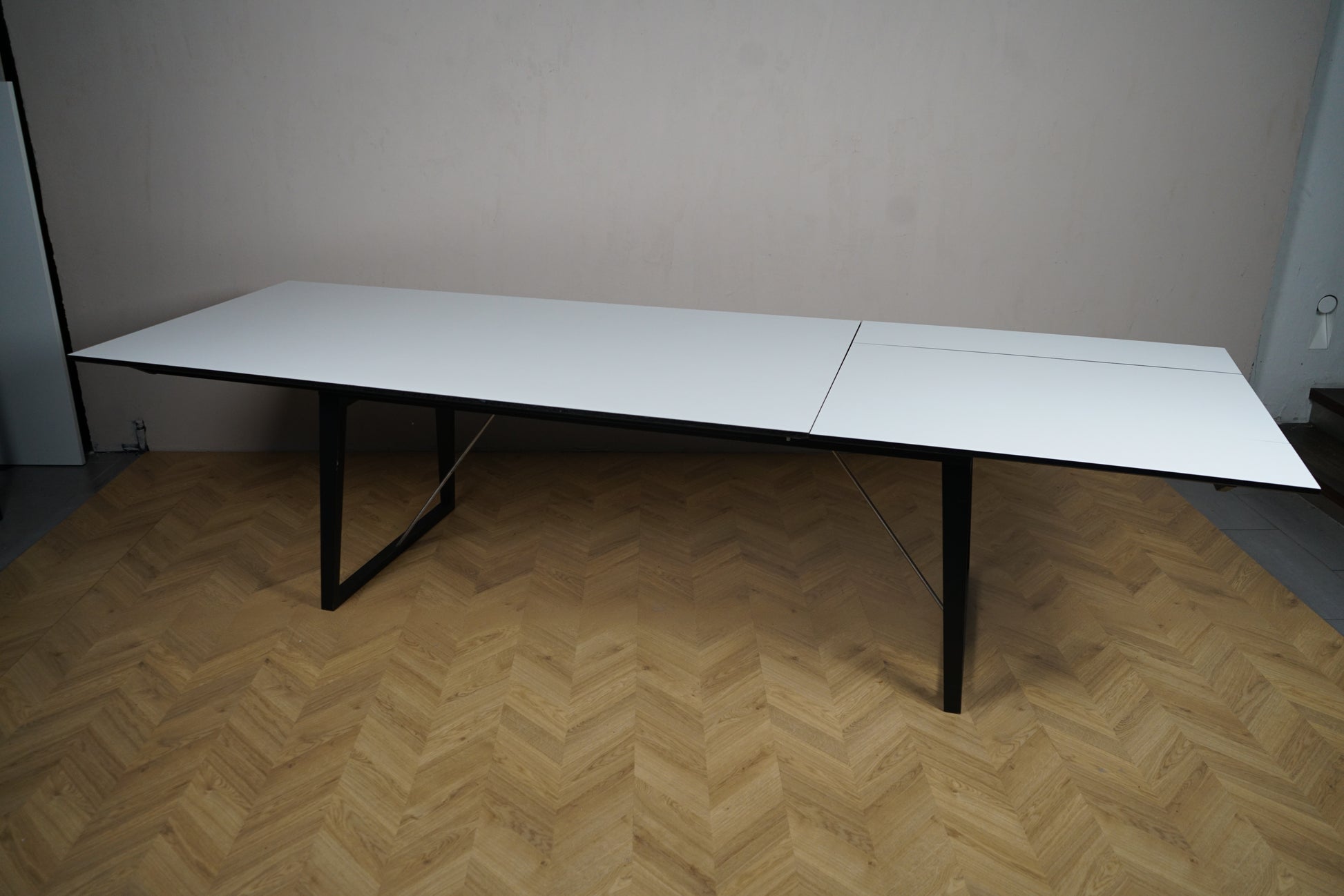 Skovby konferencebord i hvid laminat og sort stel set skråt på afstand, udtræksbord til møder og spisning.